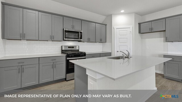 kitchen with decorative backsplash, stainless steel appliances, sink, and gray cabinetry