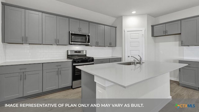 620 Radley Rd, Lockhart, TX 78644 - kitchen featuring stainless steel appliances, a sink, gray cabinets, light wood finished floors, and tasteful backsplash
