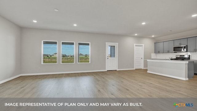 kitchen featuring gray cabinets, a center island with sink, light hardwood / wood-style flooring, and appliances with stainless steel finishes