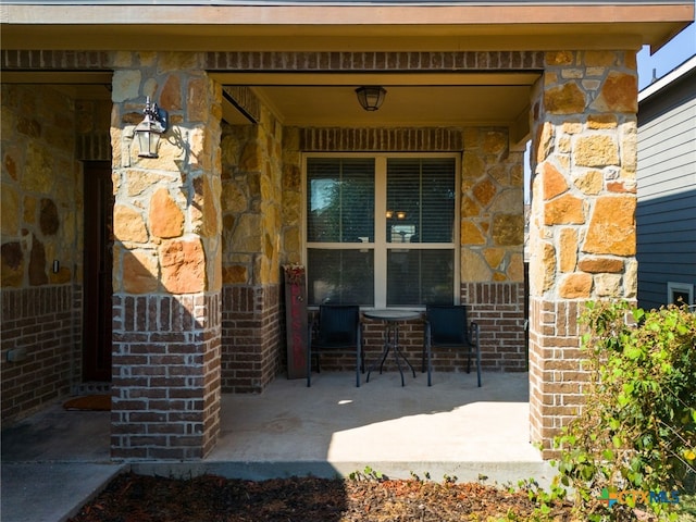 property entrance featuring stone siding, brick siding, and a porch