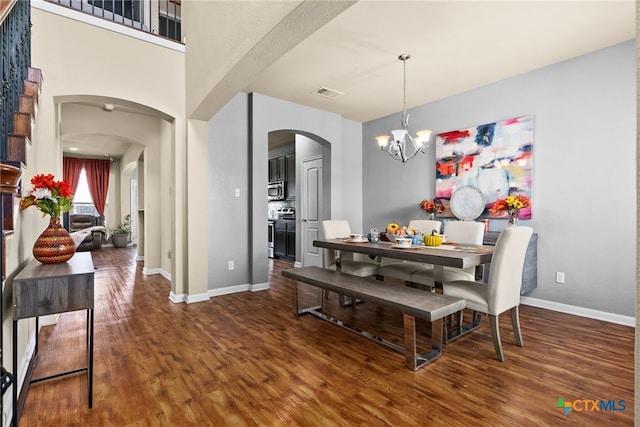 dining space with wood finished floors, baseboards, visible vents, an inviting chandelier, and arched walkways