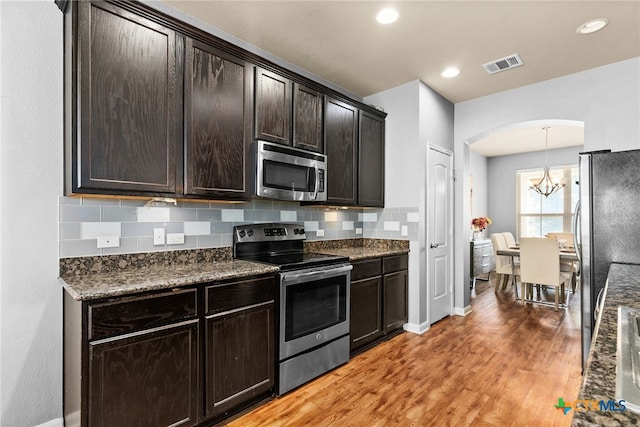 kitchen with tasteful backsplash, visible vents, light wood-style flooring, an inviting chandelier, and stainless steel appliances