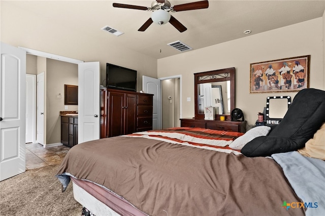 bedroom with visible vents, carpet flooring, ensuite bath, and a ceiling fan