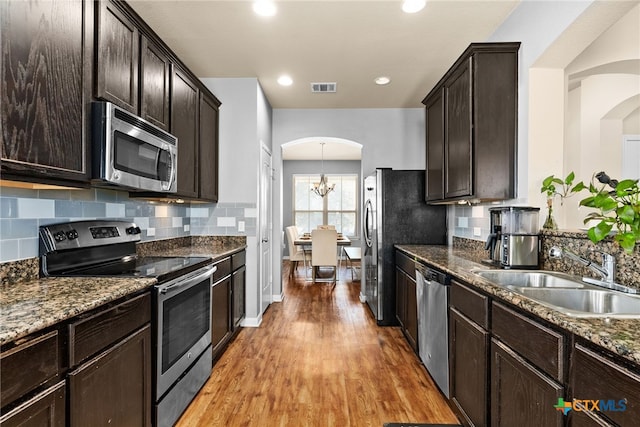 kitchen with visible vents, a sink, arched walkways, light wood-style floors, and appliances with stainless steel finishes