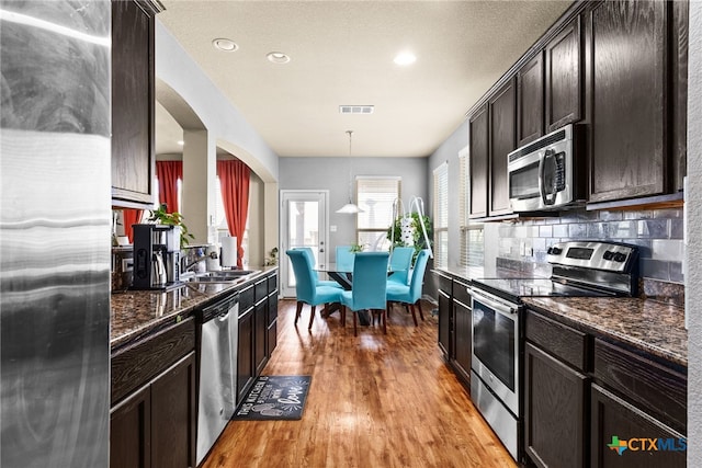 kitchen with visible vents, light wood-style flooring, a sink, tasteful backsplash, and appliances with stainless steel finishes