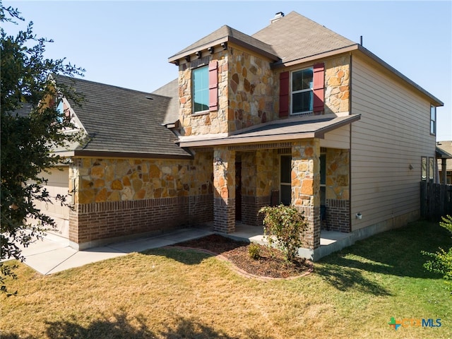 view of front of house featuring stone siding, a garage, and a front yard