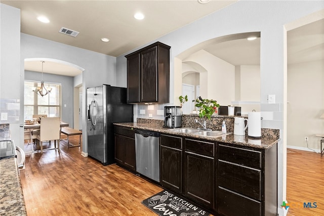 kitchen with visible vents, a sink, dark stone counters, appliances with stainless steel finishes, and light wood finished floors