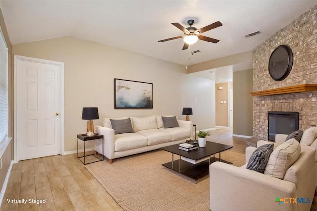 living room with light wood-style floors, a fireplace, and visible vents