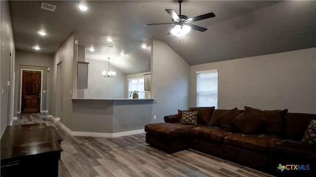 living room with vaulted ceiling, ceiling fan with notable chandelier, and hardwood / wood-style floors