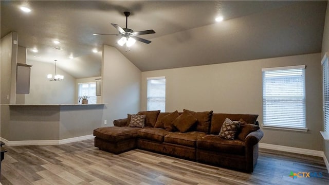 living room featuring ceiling fan with notable chandelier, vaulted ceiling, and hardwood / wood-style floors