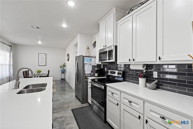 kitchen with appliances with stainless steel finishes, sink, white cabinets, and decorative backsplash