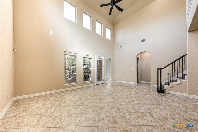 26815 Tulip Mdw, Boerne, TX 78015 - unfurnished living room featuring a ceiling fan, arched walkways, a towering ceiling, and stairway