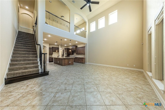 26815 Tulip Mdw, Boerne, TX 78015 - unfurnished living room with a ceiling fan, a high ceiling, stairway, and light tile patterned floors