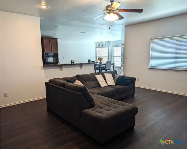 living room with dark hardwood / wood-style floors and ceiling fan with notable chandelier