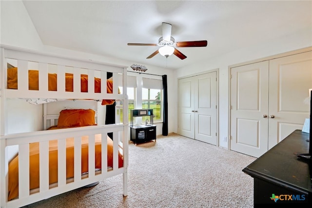 bedroom with ceiling fan, carpet flooring, and two closets