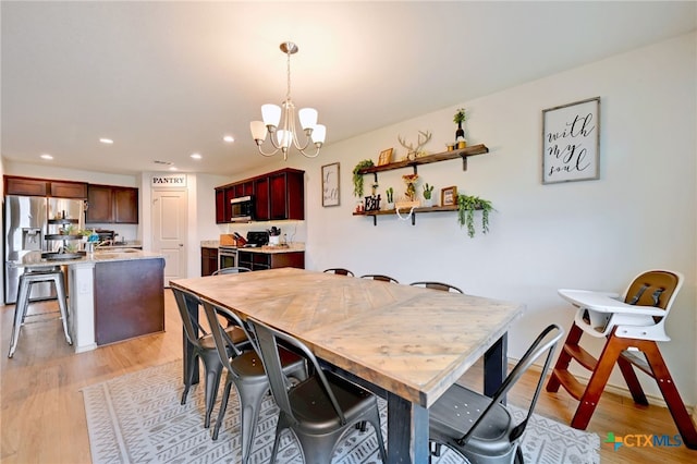 dining space with light hardwood / wood-style flooring and a notable chandelier