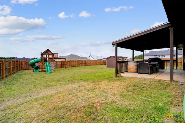 view of yard featuring a patio area, a playground, and a storage shed