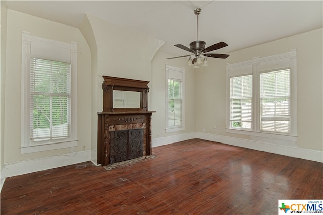 unfurnished living room featuring dark wood-type flooring and ceiling fan