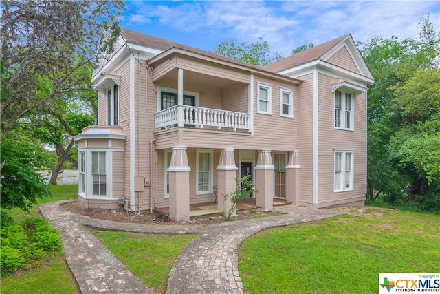 view of front of home with a balcony and a front yard