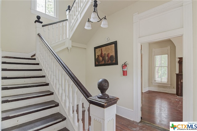 stairway with a chandelier, a wealth of natural light, and hardwood / wood-style flooring