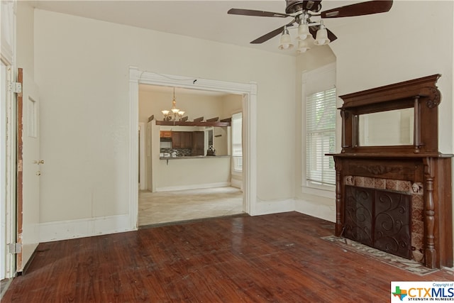 unfurnished living room with ceiling fan with notable chandelier and hardwood / wood-style flooring