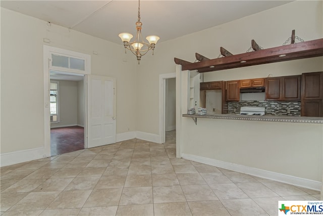 kitchen with white range oven, an inviting chandelier, decorative backsplash, light tile patterned flooring, and decorative light fixtures