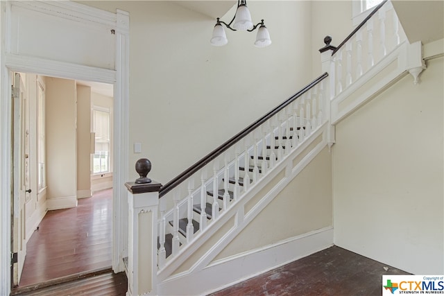 staircase with hardwood / wood-style flooring and an inviting chandelier