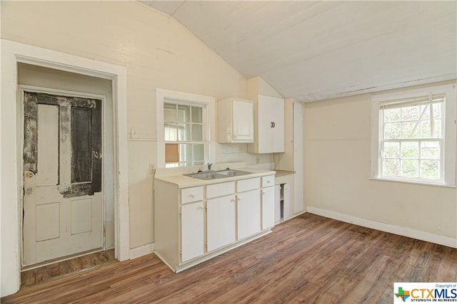 kitchen with hardwood / wood-style floors, white cabinetry, lofted ceiling, and sink