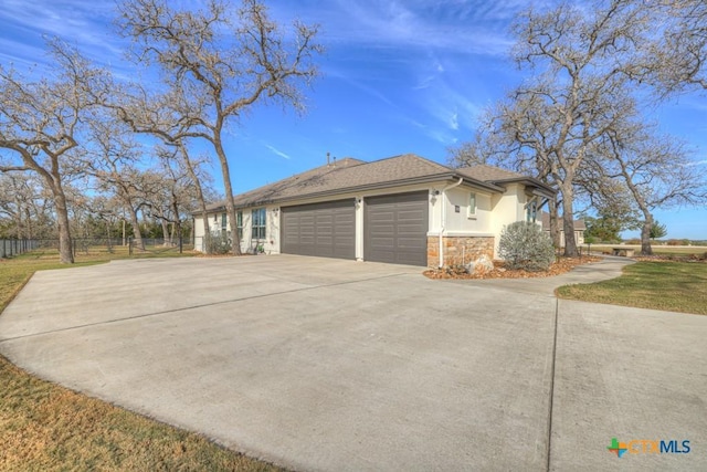 view of home's exterior with roof with shingles, stucco siding, concrete driveway, a garage, and stone siding