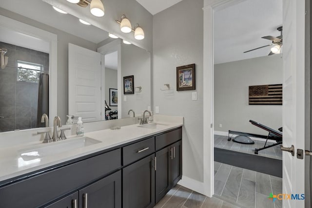 bathroom with double vanity, a sink, a ceiling fan, and baseboards