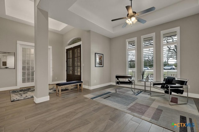 sitting room with light wood-style floors, baseboards, a raised ceiling, and french doors