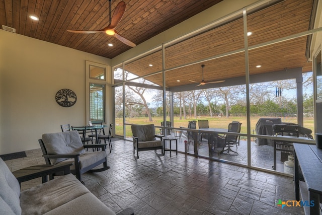 sunroom / solarium with wood ceiling, a ceiling fan, and a wealth of natural light