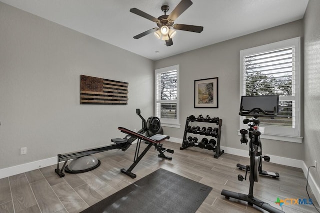 exercise area featuring baseboards, a ceiling fan, and wood finish floors