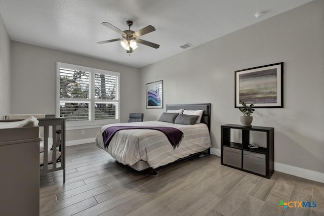 bedroom with light wood-style floors, visible vents, baseboards, and a ceiling fan