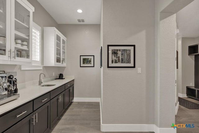 bar with recessed lighting, visible vents, a sink, light wood-type flooring, and baseboards