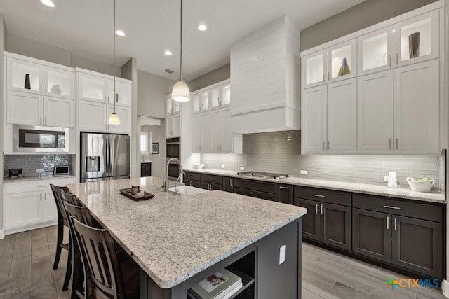 kitchen featuring stainless steel appliances, a center island with sink, and white cabinetry