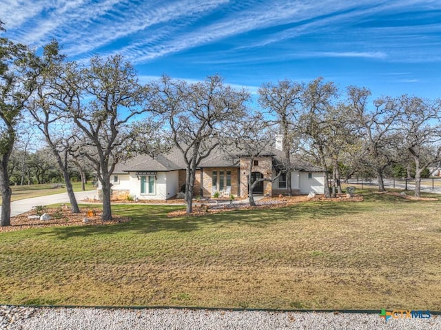 ranch-style home featuring driveway, stone siding, and a front yard