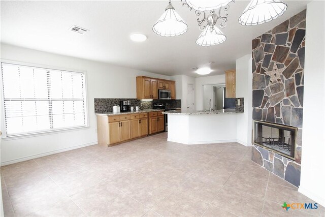 2216 Smith Bluff Rd, Salado, TX 76571 - kitchen featuring stainless steel appliances, decorative backsplash, light stone countertops, light tile patterned floors, and a fireplace