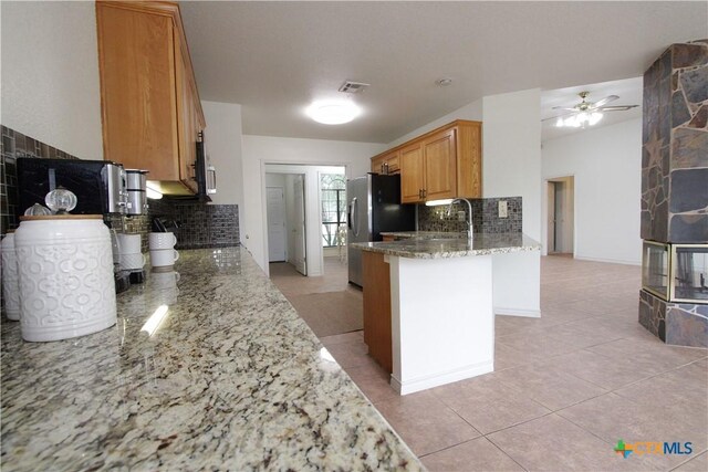 2216 Smith Bluff Rd, Salado, TX 76571 - kitchen with backsplash, light stone countertops, a peninsula, ceiling fan, and light tile patterned flooring
