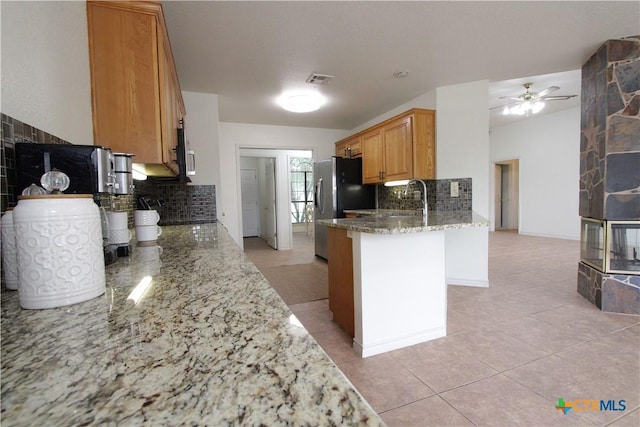 2216 Smith Bluff Rd, Salado, TX 76571 - kitchen featuring tasteful backsplash, light stone counters, a peninsula, ceiling fan, and light tile patterned flooring