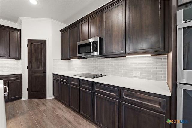 kitchen with black electric stovetop, crown molding, backsplash, dark brown cabinets, and light hardwood / wood-style flooring