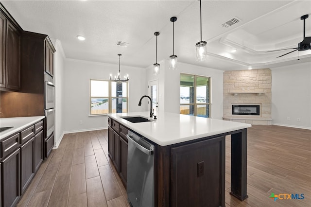 kitchen featuring stainless steel appliances, sink, dark hardwood / wood-style floors, an island with sink, and a fireplace