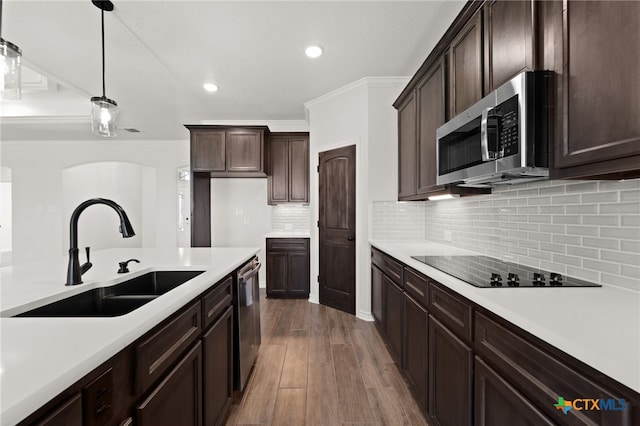 kitchen with stainless steel appliances, backsplash, decorative light fixtures, sink, and dark wood-type flooring