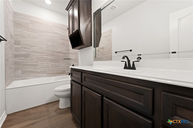 full bathroom featuring wood-type flooring, tiled shower / bath combo, toilet, and vanity