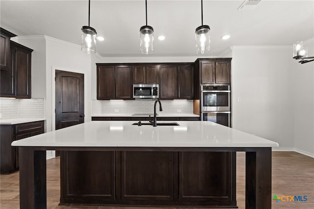 kitchen with a kitchen island with sink, appliances with stainless steel finishes, sink, and dark brown cabinets