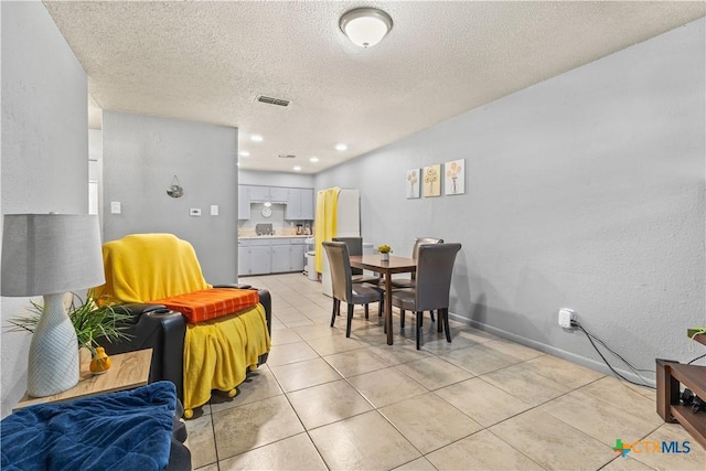 tiled dining area with a textured ceiling