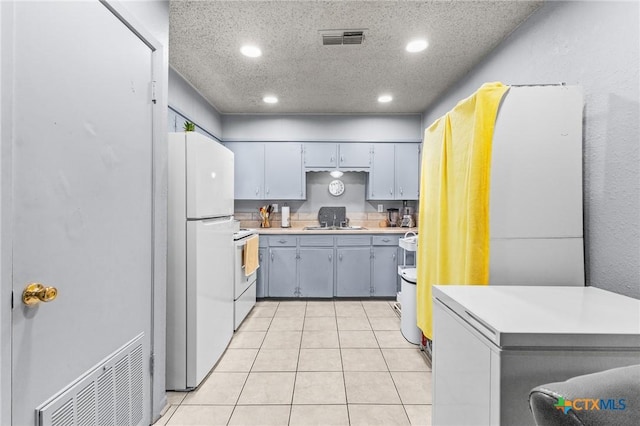 kitchen with sink, gray cabinetry, a textured ceiling, light tile patterned floors, and white appliances