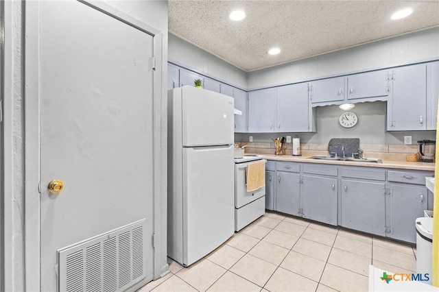 kitchen featuring sink, white appliances, gray cabinetry, a textured ceiling, and light tile patterned flooring