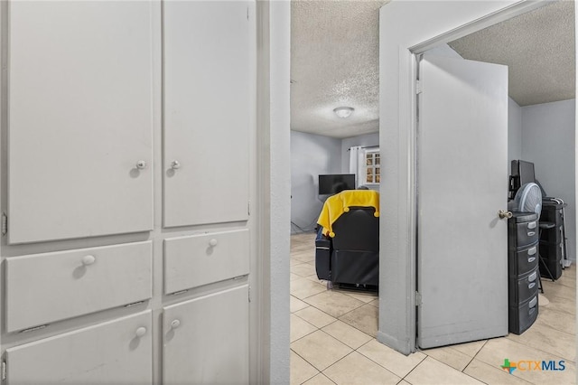 hallway with a textured ceiling and light tile patterned flooring