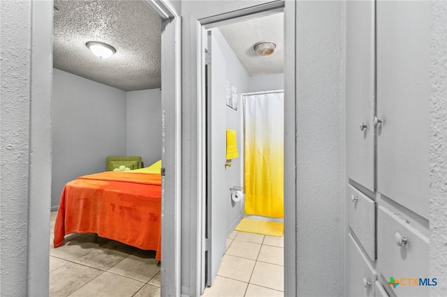 hall featuring light tile patterned floors and a textured ceiling